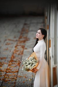 Elegant Vietnamese student in white Ao Dai reading, timeless beauty amidst classic architecture.-12