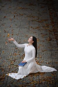 Elegant Vietnamese student in white Ao Dai reading, timeless beauty amidst classic architecture.-11