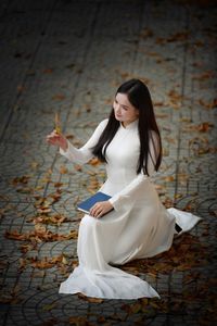Elegant Vietnamese student in white Ao Dai reading, timeless beauty amidst classic architecture.-5