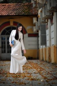 Elegant Vietnamese student in white Ao Dai reading, timeless beauty amidst classic architecture.-13