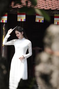 Elegant Vietnamese woman in traditional white Ao Dai, showcasing graceful beauty amidst ancient architecture.-0