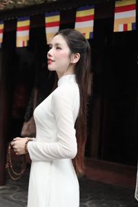 Elegant Vietnamese woman in traditional white Ao Dai, showcasing graceful beauty amidst ancient architecture.-5