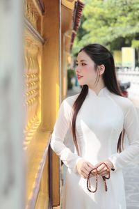 Elegant Vietnamese woman in traditional white Ao Dai, showcasing graceful beauty amidst ancient architecture.-4