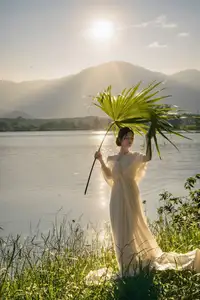 Golden Hour Serenity: Woman in White Dress Embracing Nature's Beauty by the Lake at Sunset.-9