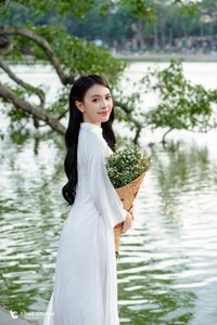 Elegant Vietnamese girl in traditional white Ao Dai by the lake, embodying cultural beauty-3