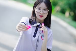 Radiant Youth: Girl in Uniform Playfully Blowing Bubbles in Lush Greenery 1000019736-1