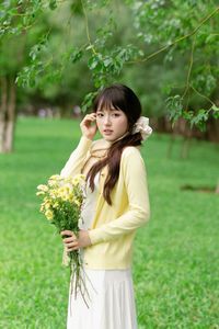 Pure Young Woman with Vibrant Yellow Flowers: Natural Beauty in a Lush Green Setting 1000019709-2