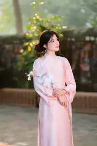 Elegant Vietnamese Beauty: Young Woman Gracefully Posing in Pink Ao Dai with White Orchids 1000026874-3